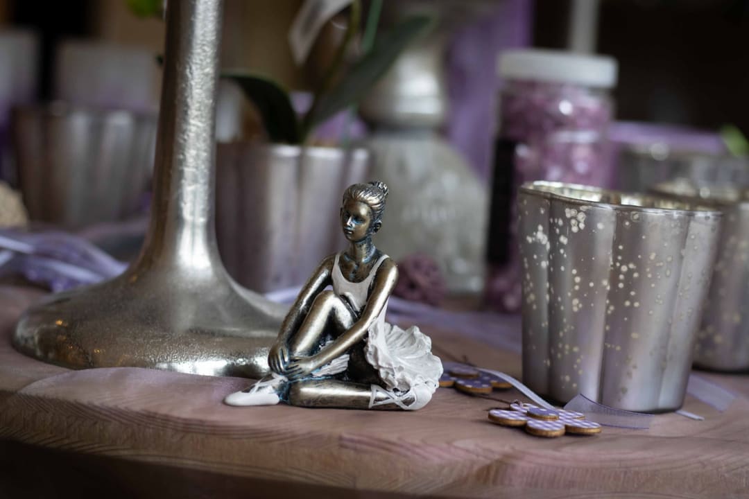 Silberne Ballerina-Figur zwischen Kerzenleuchter und silbernen Teelichtgläsern